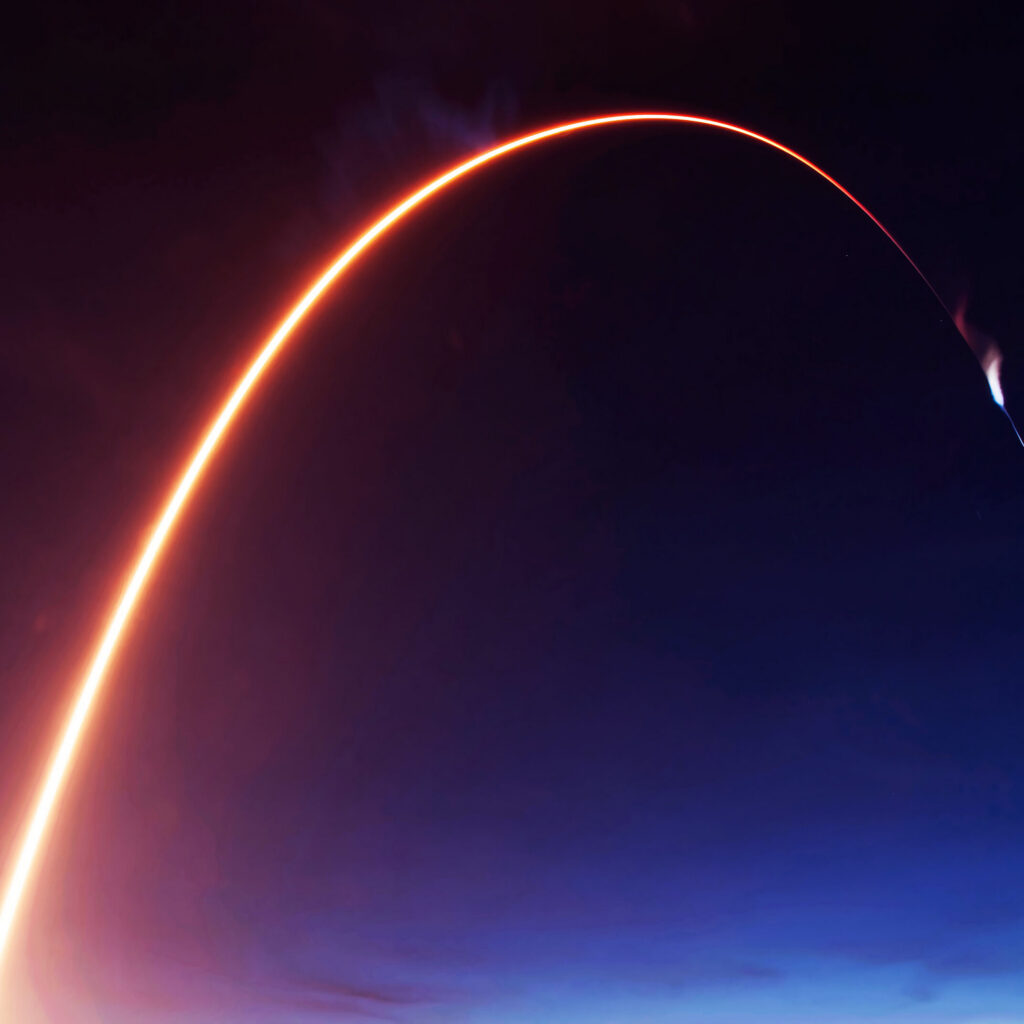Ballistic missile trajectory arc ascending through Earth’s atmosphere at night.