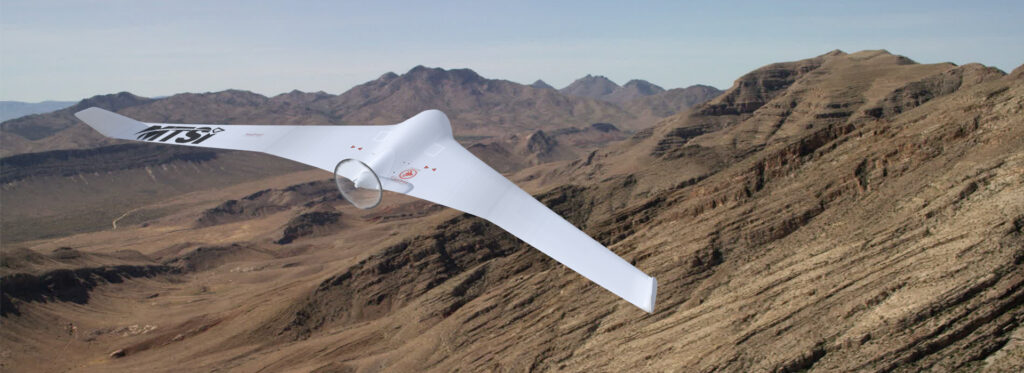 Unmanned aerial vehicle flying above mountainous desert terrain.