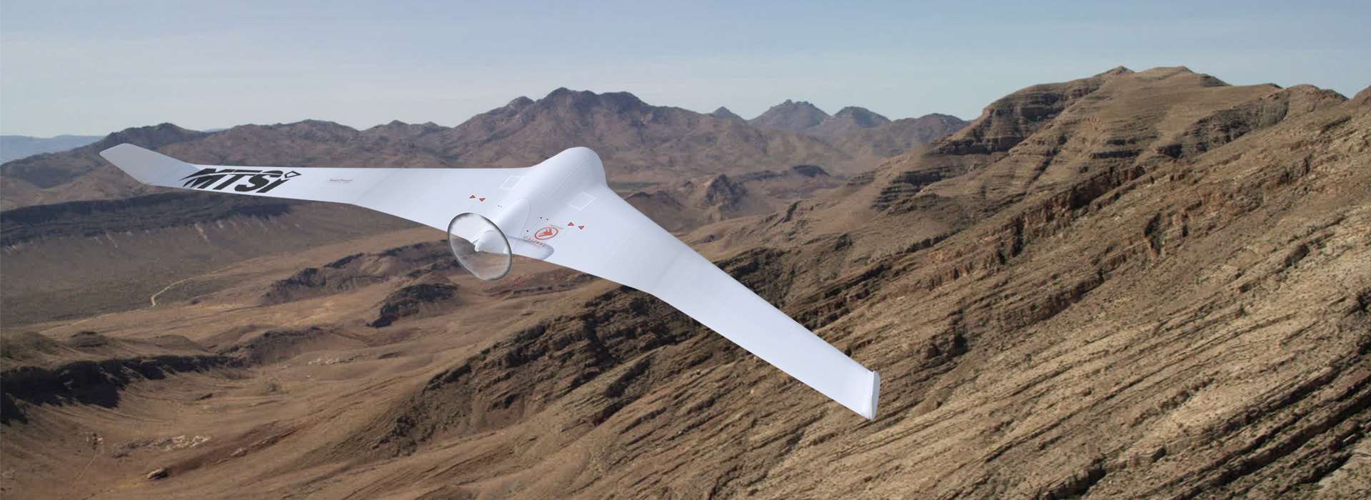 Unmanned aerial vehicle flying above mountainous desert terrain.