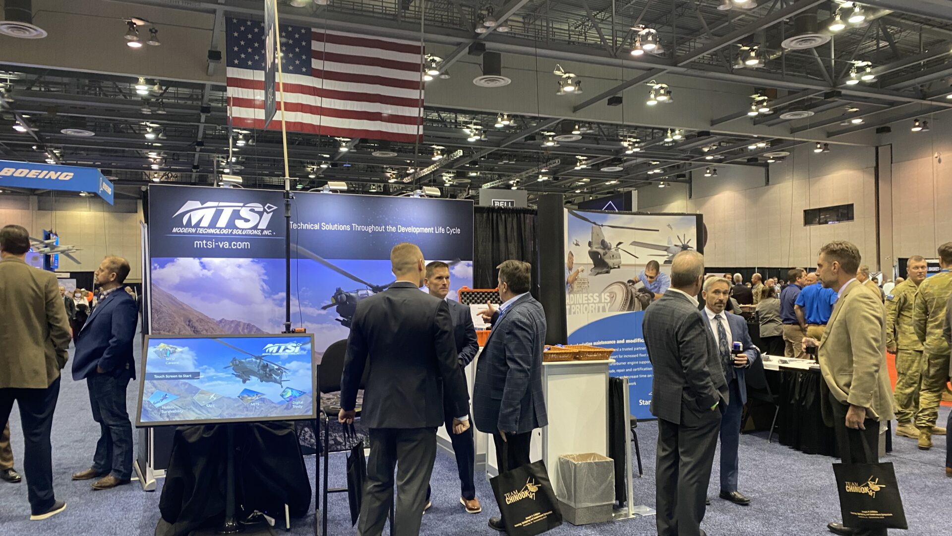 Attendees networking at aerospace and defense industry conference exhibit hall.