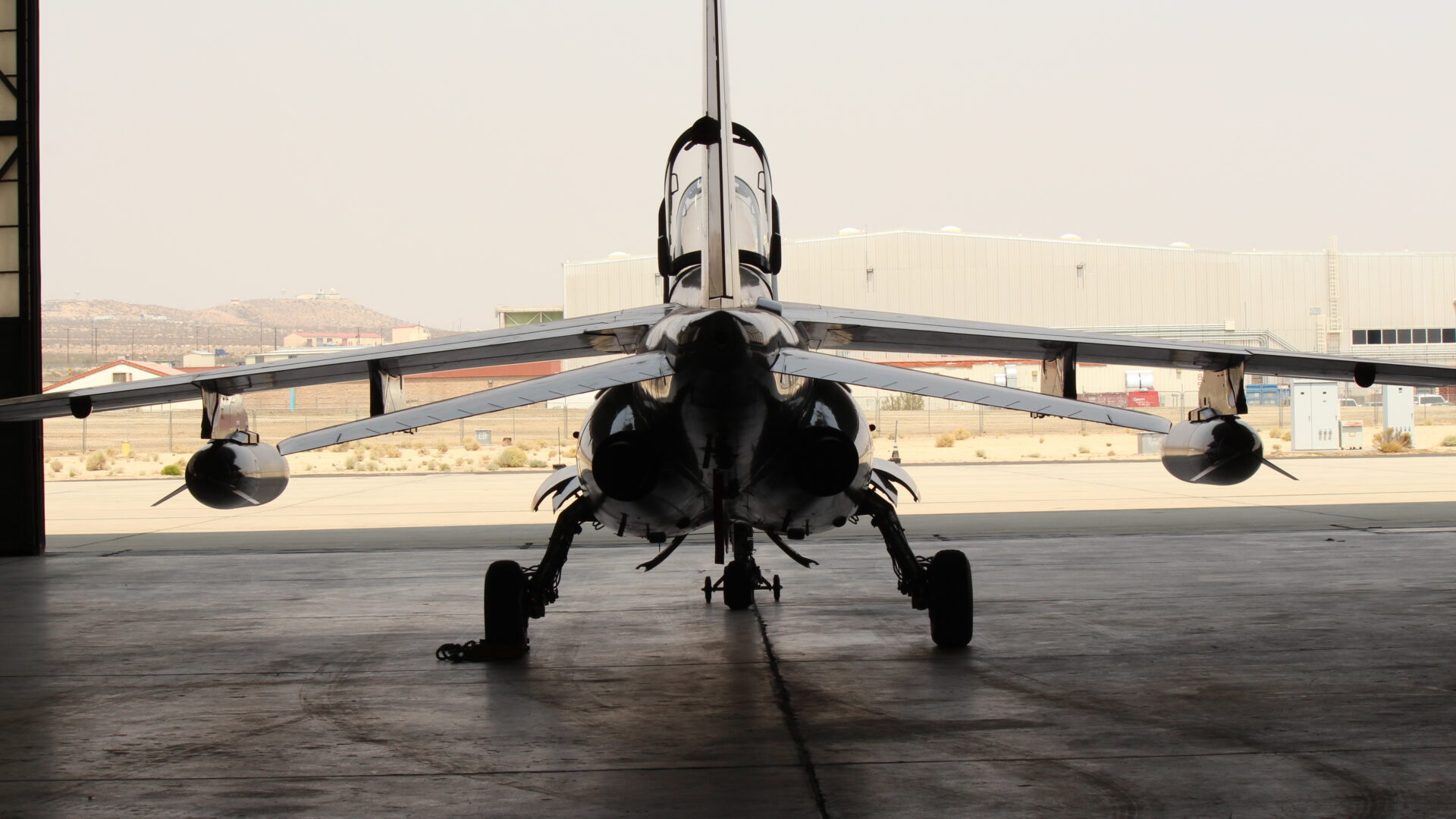 Rear view of military aircraft positioned inside an aircraft hangar.