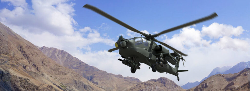 Military helicopter flying above mountainous terrain under a partly cloudy sky.