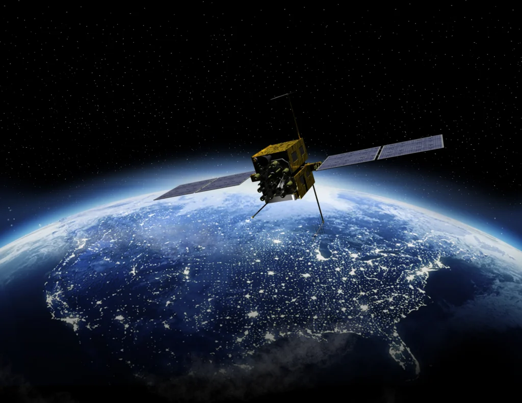 Satellite orbiting above Earth with illuminated city lights visible across the planet's surface.