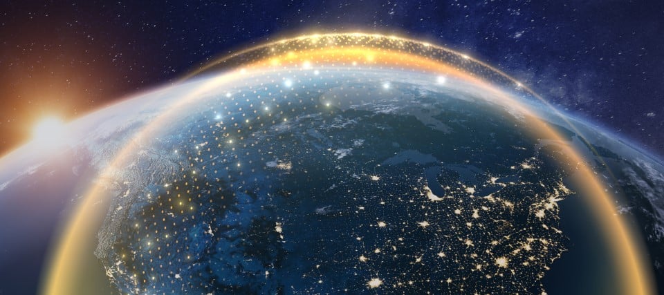 View of Earth at night with illuminated atmospheric horizon and city lights.