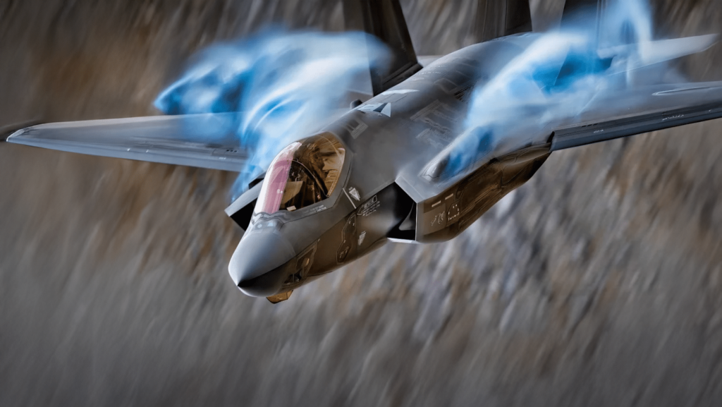Military aircraft in high-speed flight with visible aerodynamic vapor over the wings.