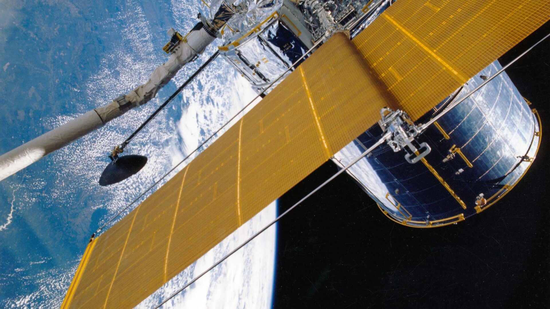 Satellite in orbit above Earth with large solar panels extended.