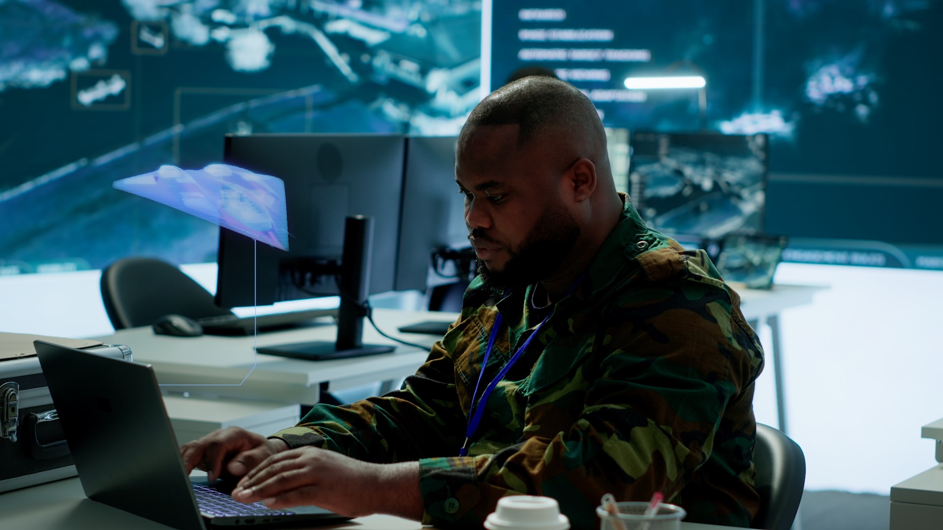 Military analyst working at computer workstation inside advanced command and control operations center.